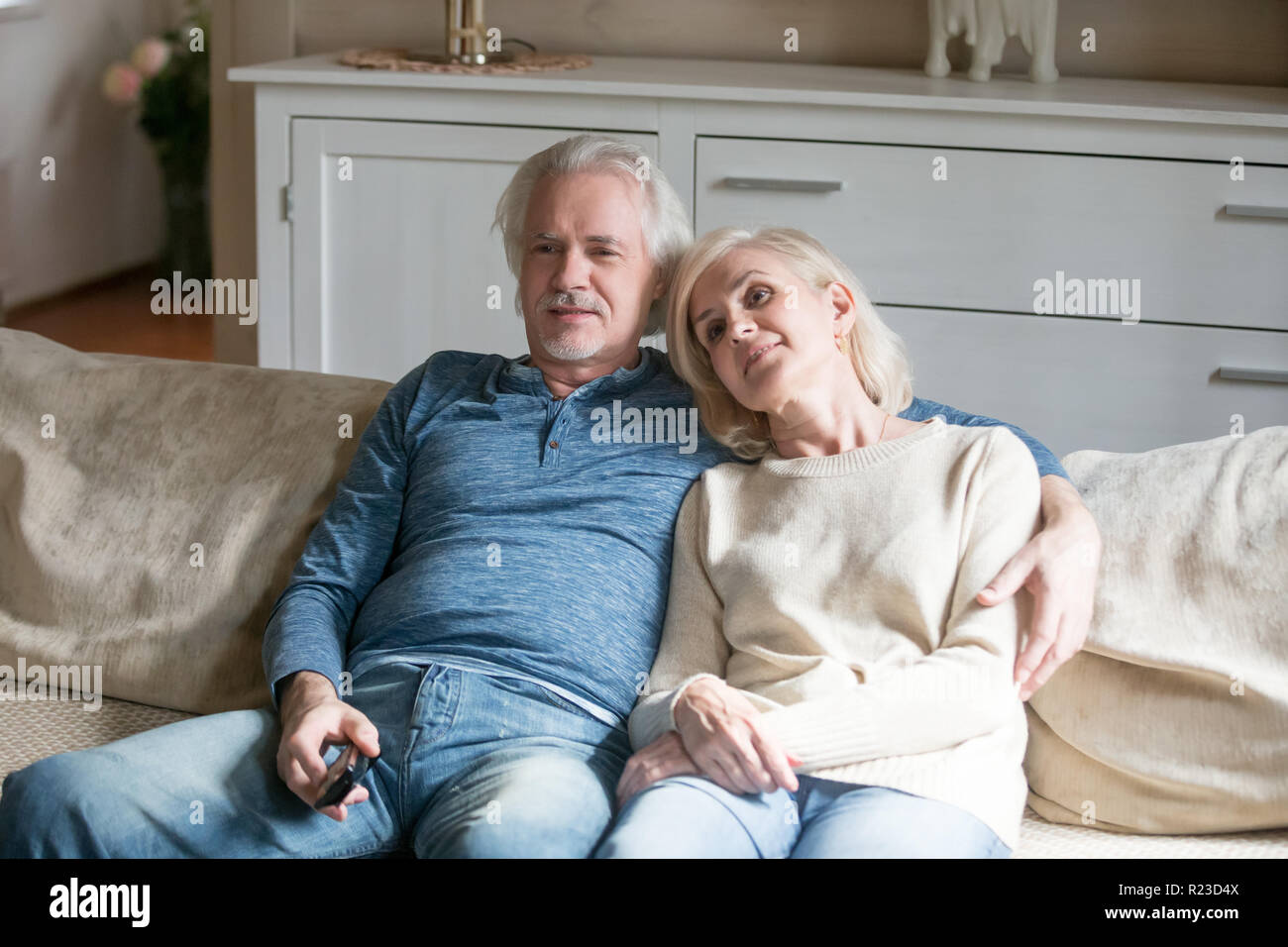 Glücklich im Alter von Paar auf dem gemütlichen Sofa zu Hause liegen sie auf einem Fernsehgerät, älterer Mann und Frau kuscheln Relaxen auf dem Sofa verbringen romantische Zeit am Wochenende, Stockfoto