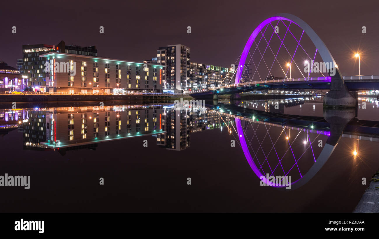 Glasgow, Schottland, Großbritannien - 4. November 2018: moderne Apartment Gebäude sind in den Fluss Clyde neben dem Clyde Arc Brücke in Glasgow in der Nacht wider. Stockfoto