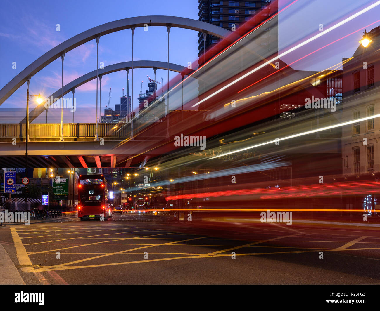 London, England, UK - 20. Oktober 2018: die roten Doppeldeckerbusse Licht hinterlassen Spuren, wie Sie entlang der Shoreditch High Street, unter London Overground' Stockfoto