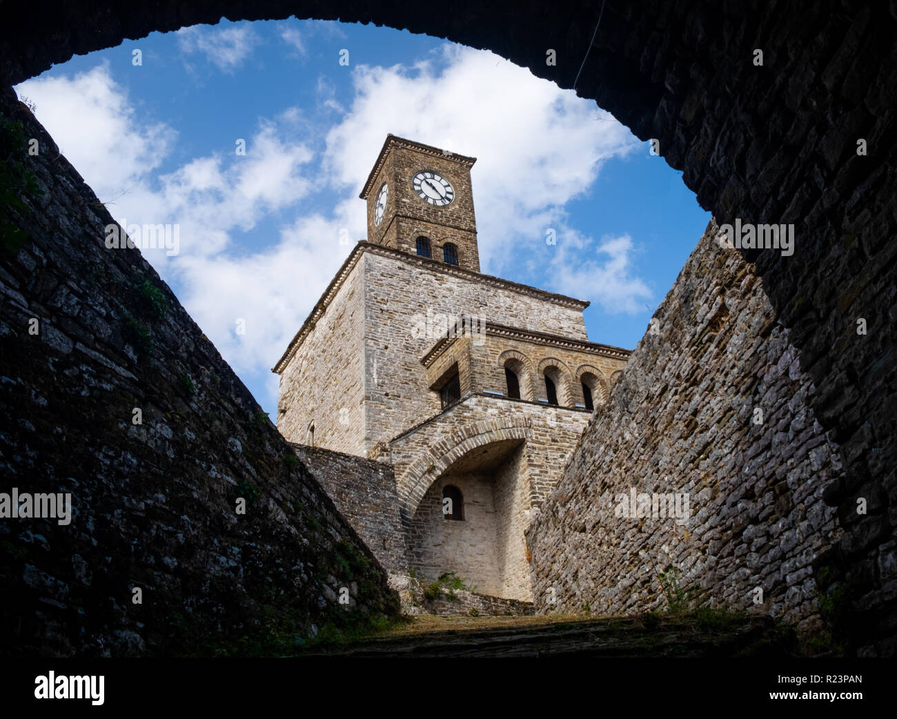 Framing durch Torbogen des Clock Tower der Festung von Gjirokastra in Albanien, mit blauem Himmel und weißen Wolken Hintergrund Stockfoto