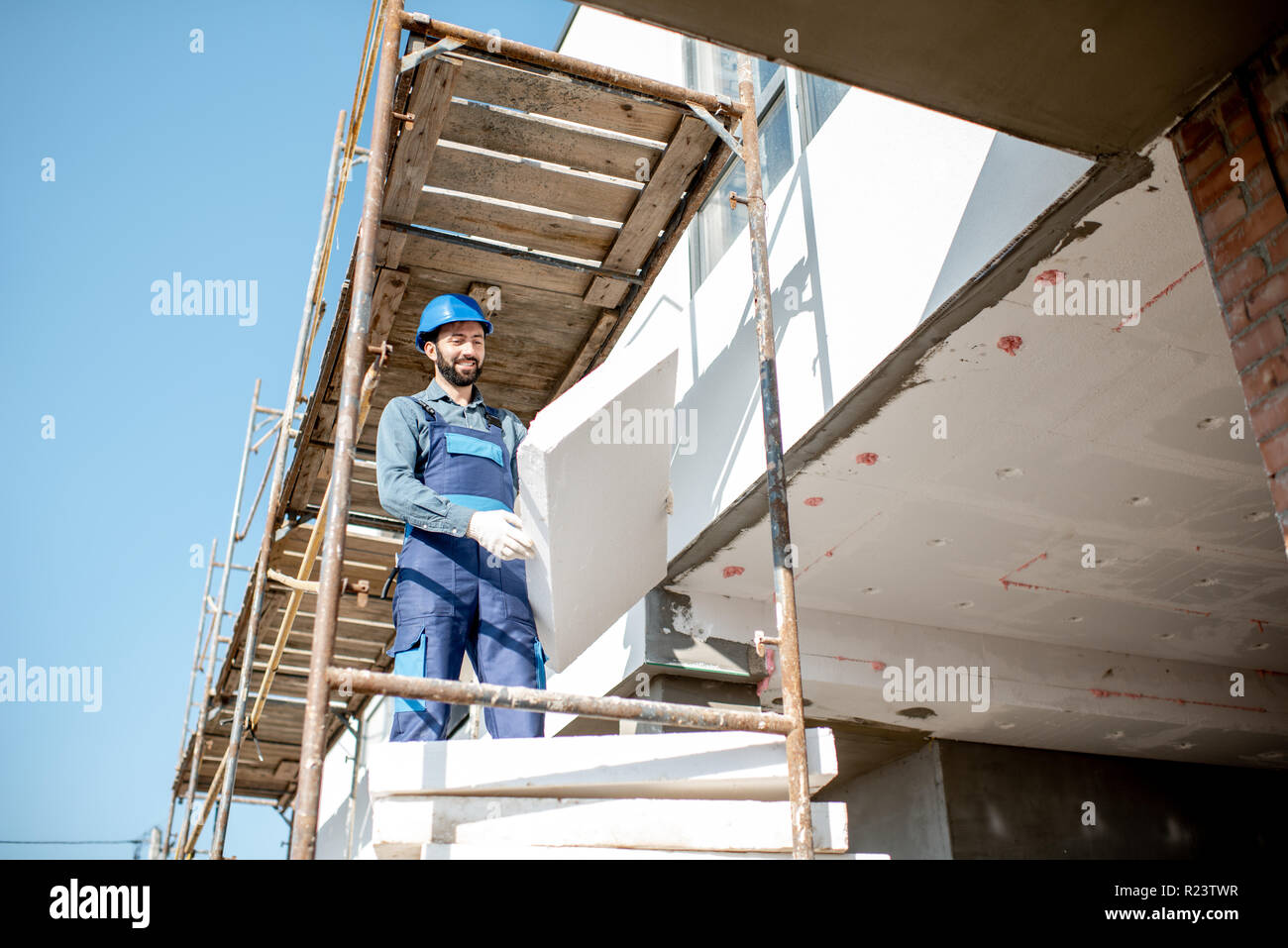 Builder Erwärmung eine Fassade mit Schaum Panels stehen auf dem Baugerüst auf der Baustelle Stockfoto