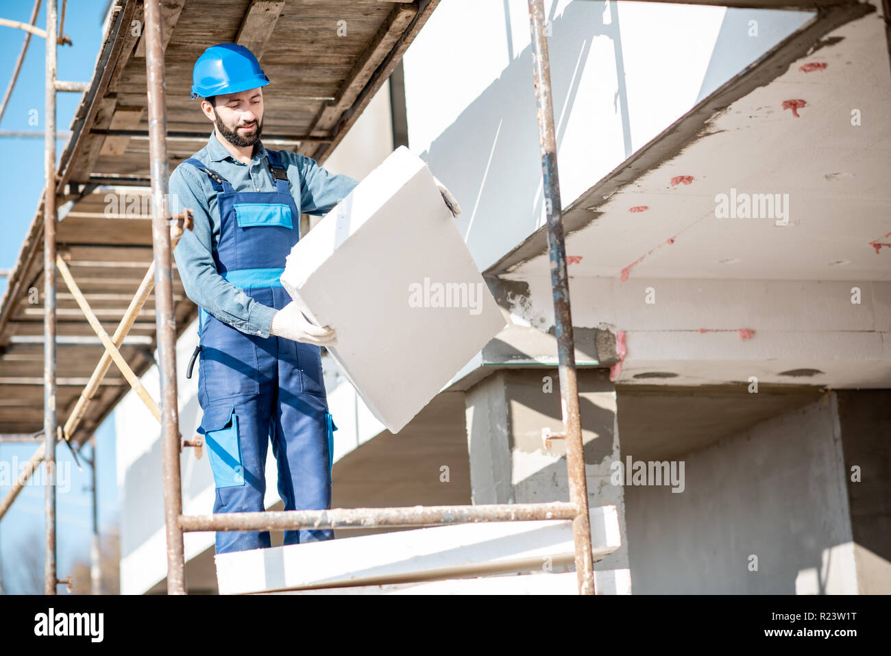 Builder Erwärmung eine Fassade mit Schaum Panels stehen auf dem Baugerüst auf der Baustelle Stockfoto