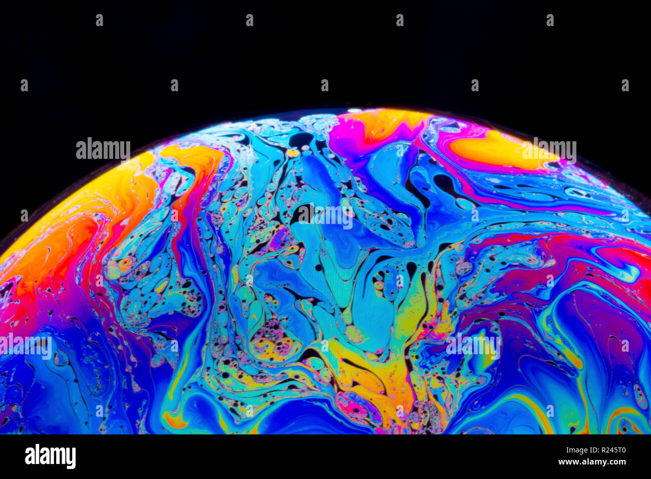 Nahaufnahme Regenbogen Farben in einer Seifenblase, wie Leerzeichen oder Planeten oder Welten auf einem schwarzen Hintergrund isoliert betrachten Stockfoto