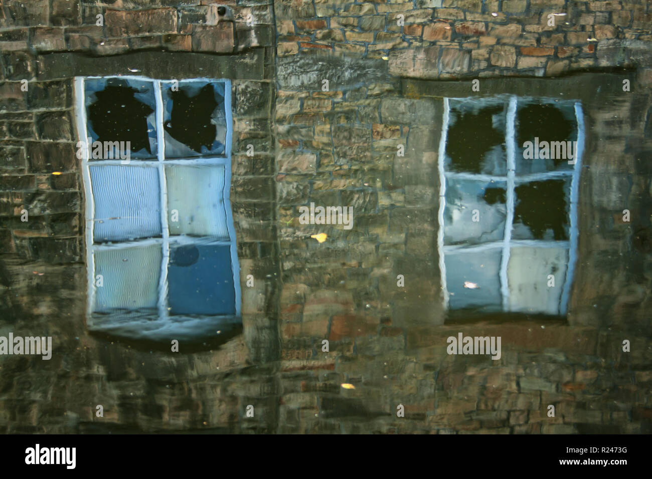 Die Reflexion der zerbrochene Fenster, an der Seite der Leeds und Liverpool Canal, Brierfield Stockfoto