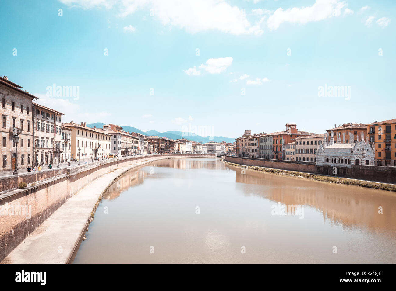 Horizontale Foto mit Blick auf den Fluss Arno, die durch die berühmten Stadt Pisa in Italien Toskana geht. Wasser ist braun. Gebäude sind auf beiden Seiten. Hügel sind im Hinterg Stockfoto