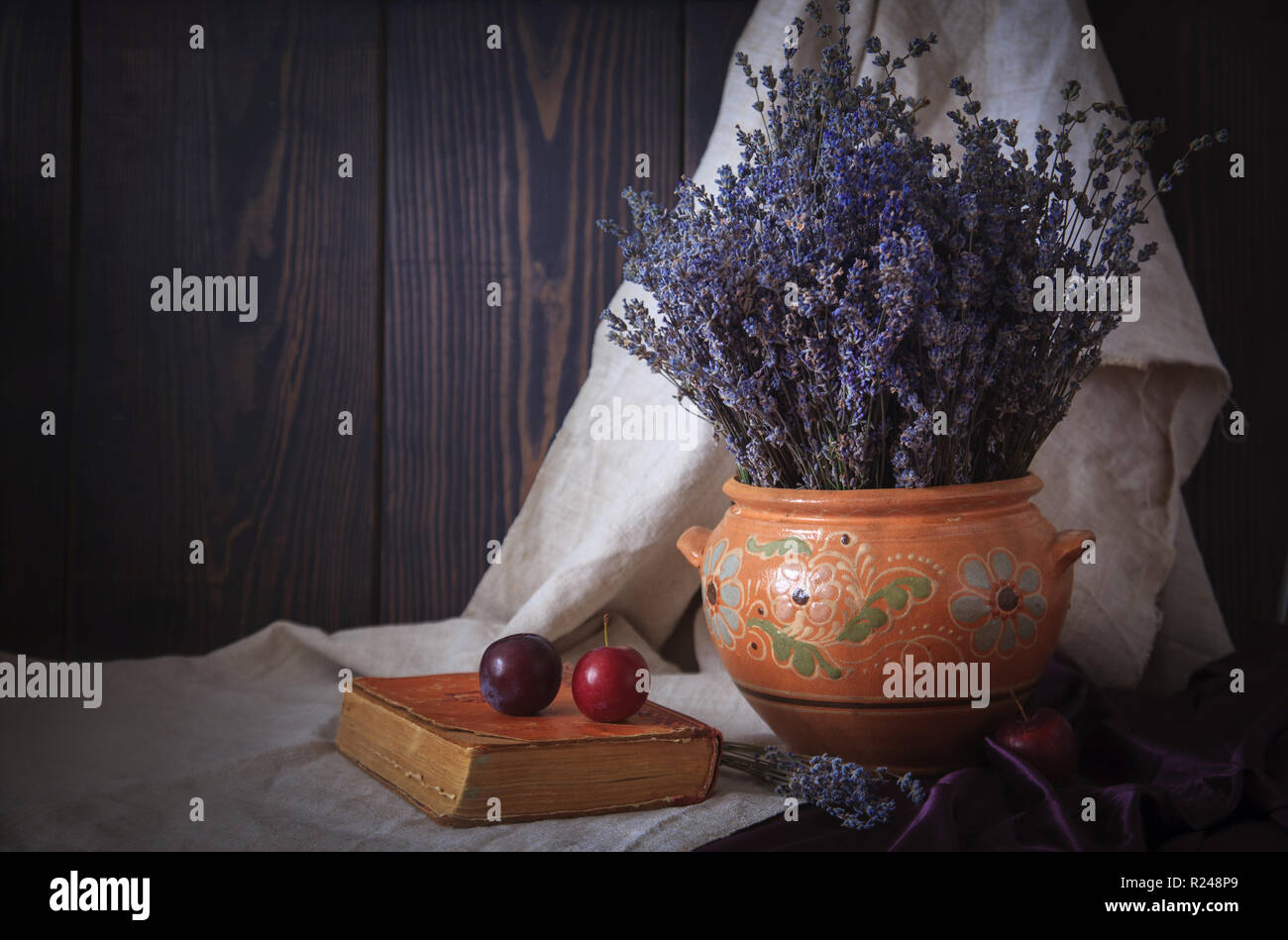 Noch immer leben mit einem Blumenstrauß aus Lavendel, ein Buch und Pflaumen auf den Tisch. Landhausstil. Stockfoto