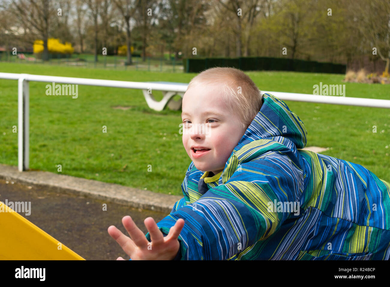 Mangels, Kinderbetreuung, Medizin und Personen Konzept - Junge mit Down-syndrom, die spielen auf einem Spielplatz. Stockfoto