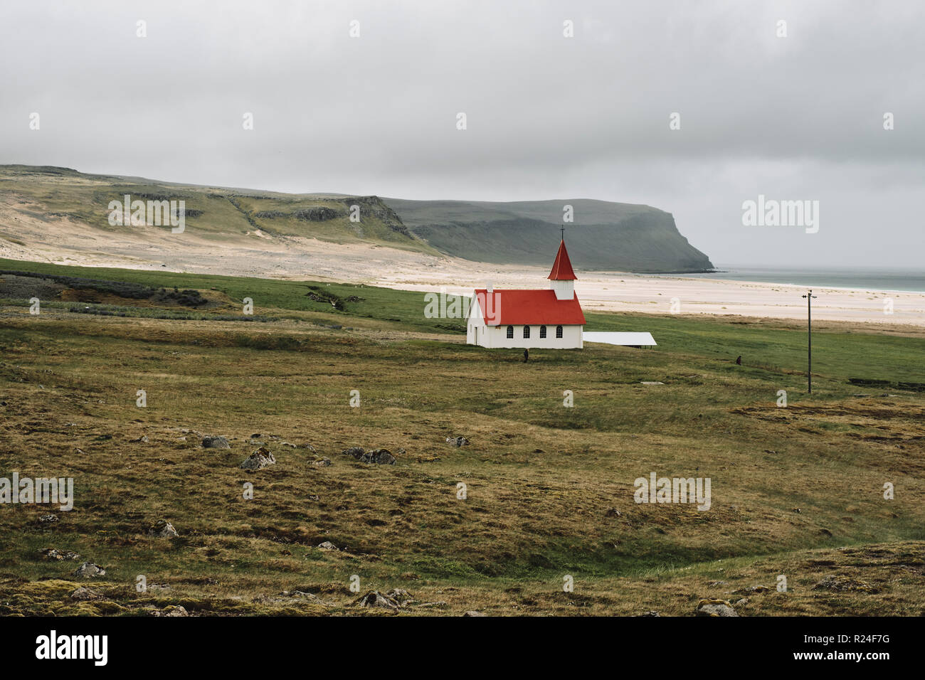 Die kleine Breidavik Kirche und Schritte in die trostlosen Low cloud Island Landschaft der Westfjorde. Stockfoto