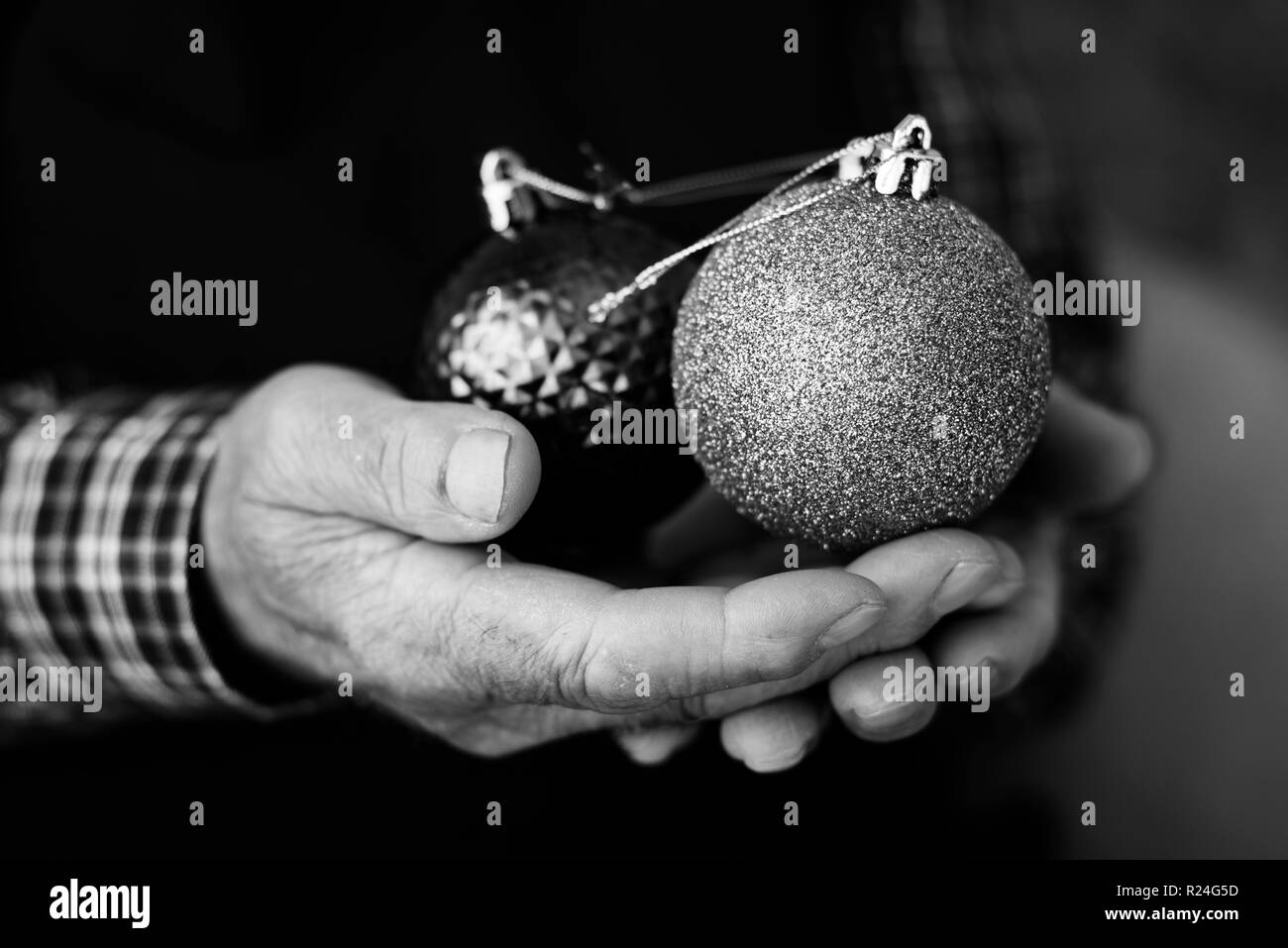 Nahaufnahme eines alten weißen Mann mit einigen Weihnachtskugeln in seine Hände, in Schwarz und Weiß Stockfoto