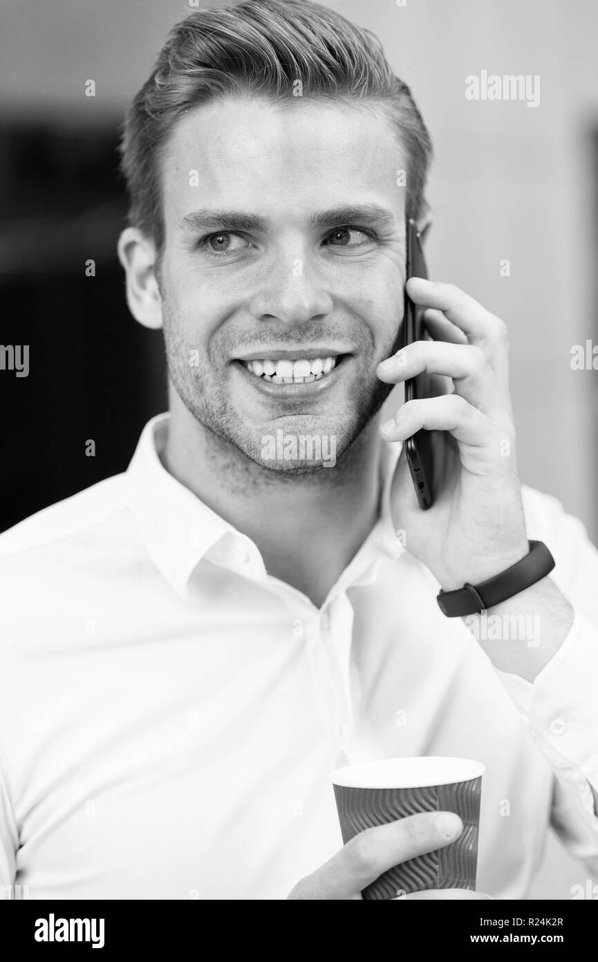 Mann sprechen auf Handy mit Kaffeetasse. Happy Geschäftsmann. In Kontakt bleiben. Ceo im Freien arbeiten für digitales Marketing. Kaffeepause. Sich um das Geschäft kümmern. Neue Technologie für das moderne Leben. Stockfoto