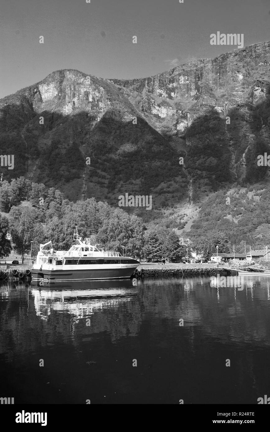 Boot auf dem Meer Pier auf der Berglandschaft in Flam, Norwegen. Kleines Schiff im Meer Hafen mit grünen Bergen. Anreise mit Wasser. Sommer und Urlaub. Wanderlust und Entdeckung. Stockfoto