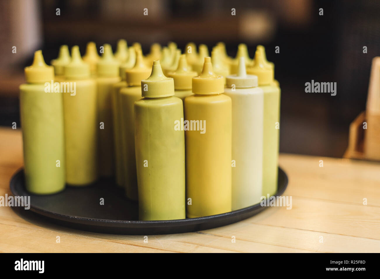 Flaschen mit Senf auf Tablett im Restaurant innen Stockfoto