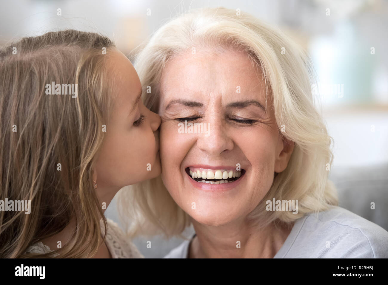 Süße kleine Enkelin küssen Lächeln alte Großmutter auf che Stockfoto