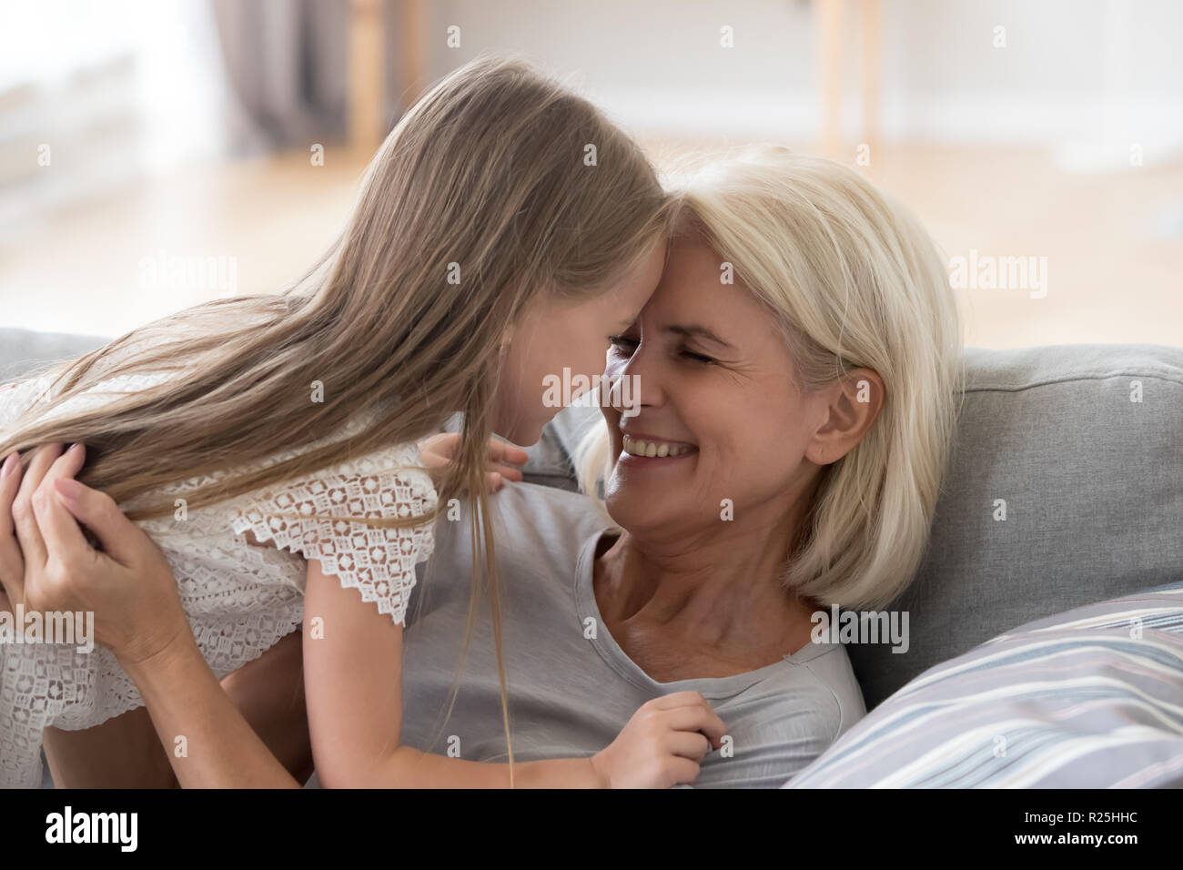 Süße Enkelin Spaß spielen mit Großmutter umarmt Stockfoto
