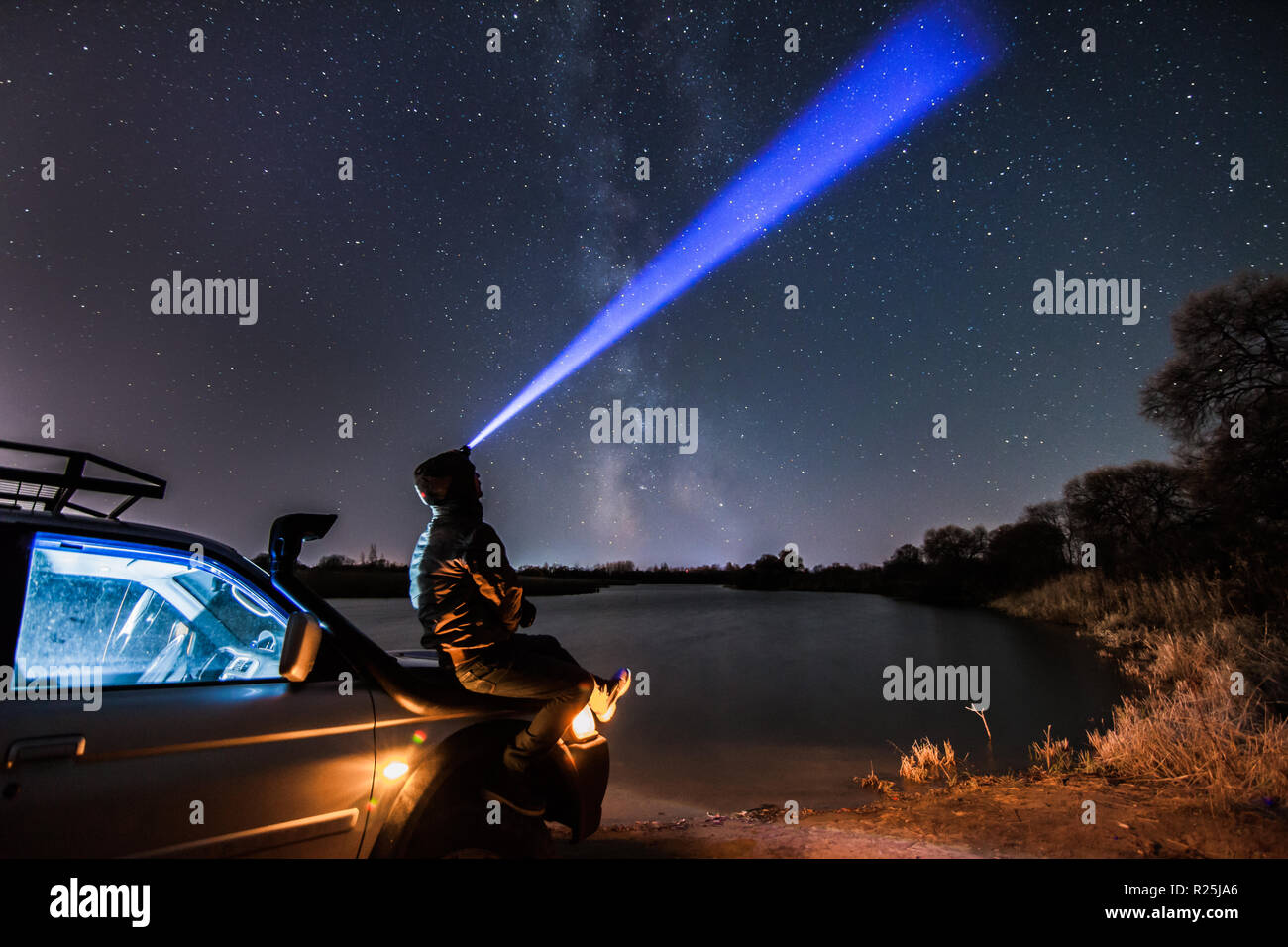 Ein Mann mit Taschenlampe auf der Suche uptsairs in den Nachthimmel und Milchstraße. Einige Körner mit hohen ISO-Werten vorhanden ist Stockfoto
