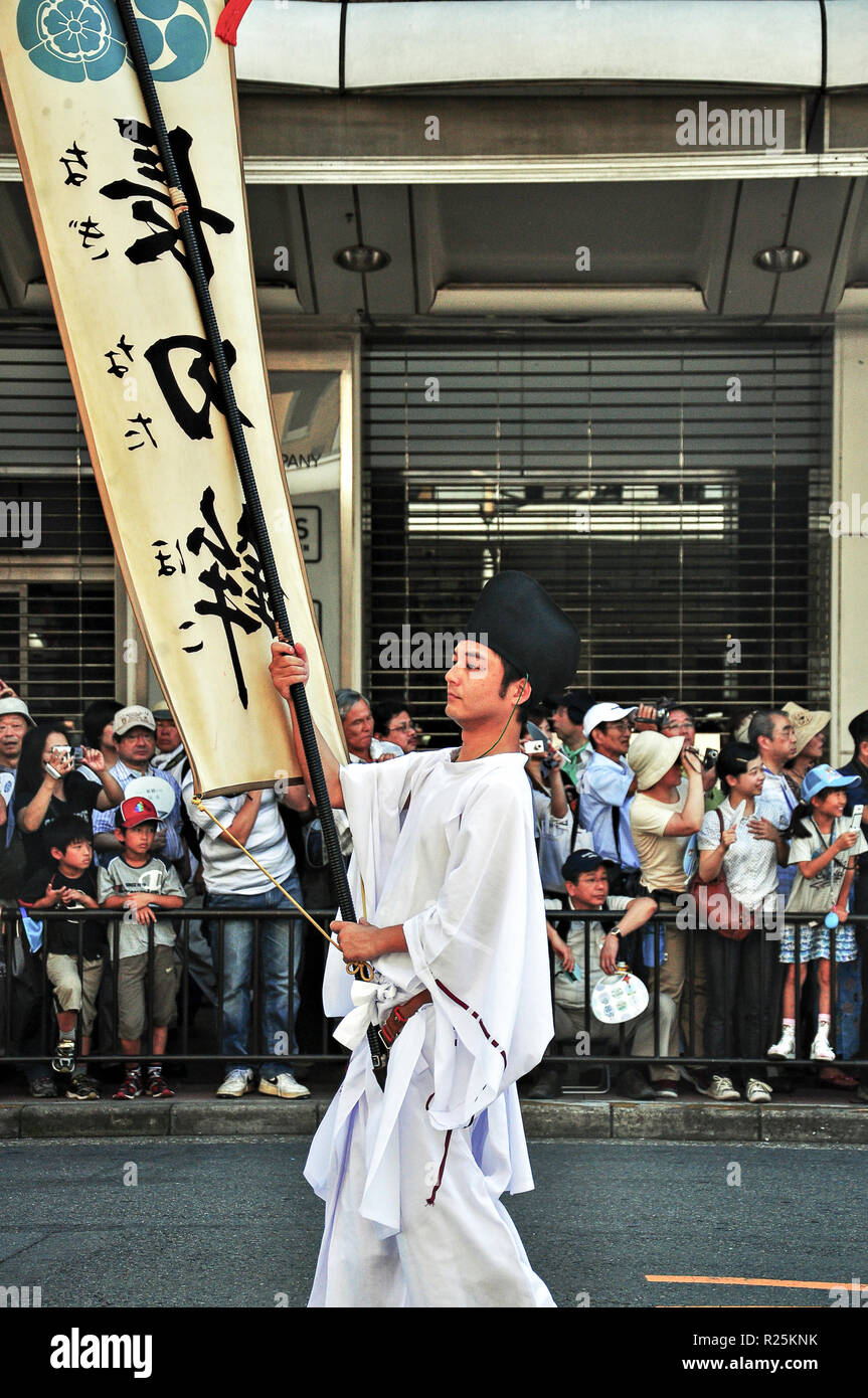 Kyoto, Japan - Juli 17, 2011: Japanische junge Mann durchlöcherte Flagge führenden die Parade in Gion Festival, Kyoto, Japan Stockfoto