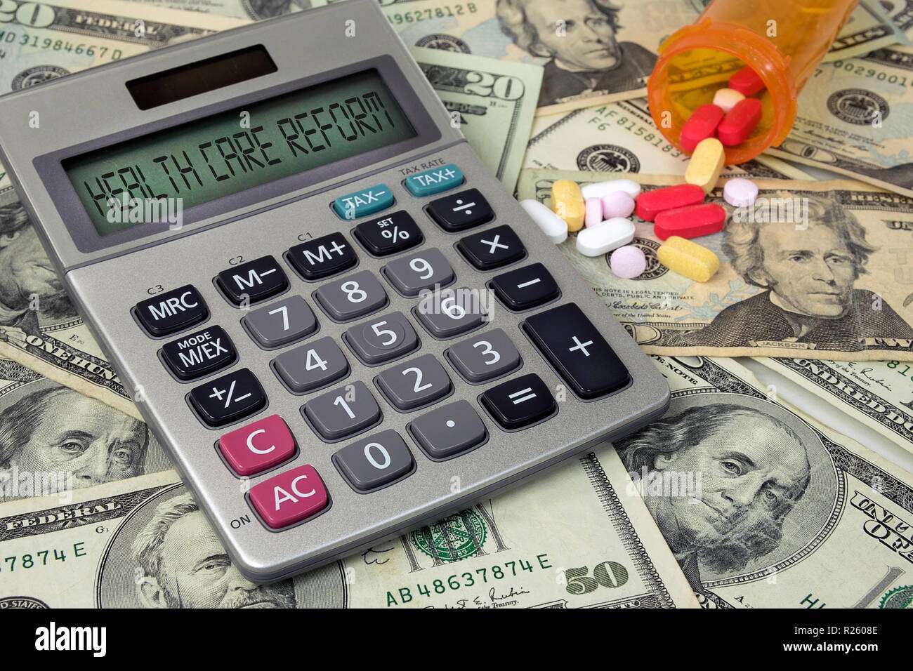 Gesundheitsreform text auf Rechner und Amerikanisches Geld mit einer Vielzahl von verschreibungspflichtigen Medikamenten aus orange Pille Flasche Stockfoto