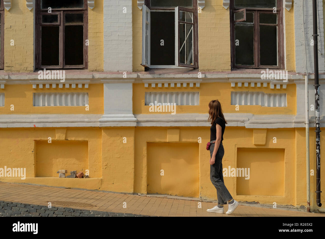 Mädchen Wanderungen entlang der alten gelben Gebäude Stockfoto