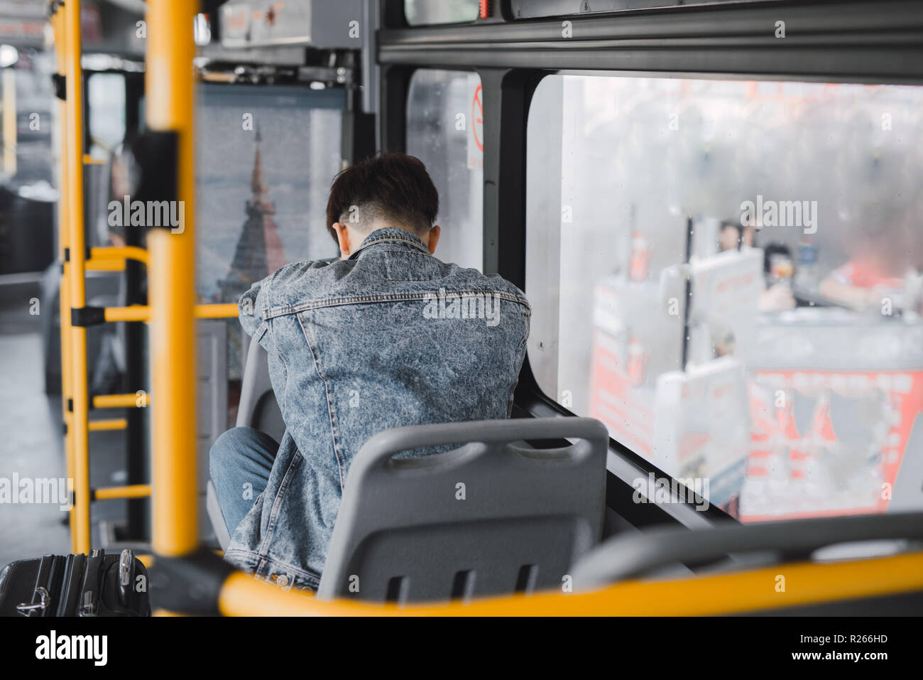 Hübscher junger Mann in eine blaue Jeansjacke mit Smartphones im Bus Stockfoto