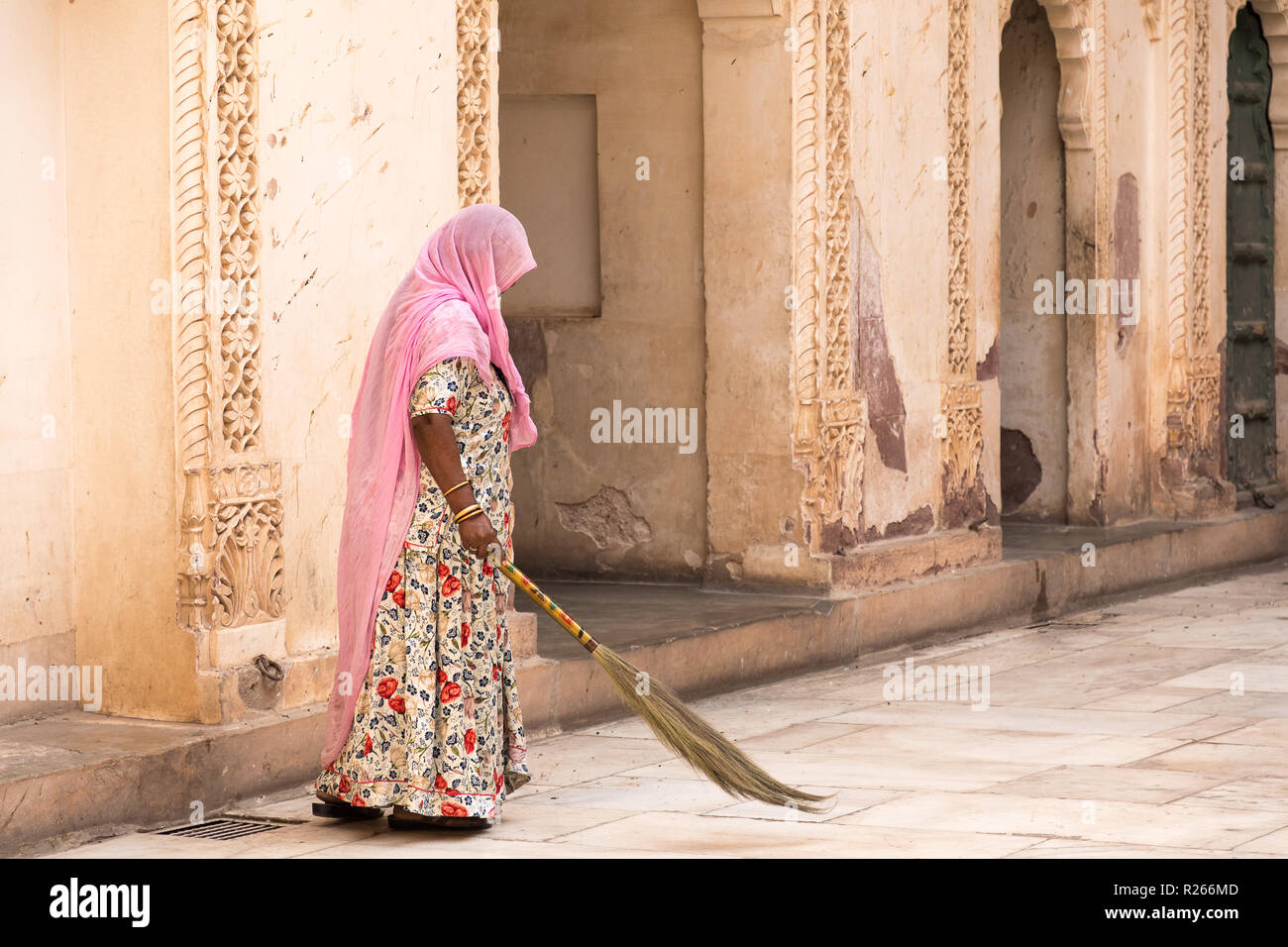 Alte Frau mit rosa Kopftuch in Sari sweeps Terrasse in Jodhpur Palace. Stockfoto