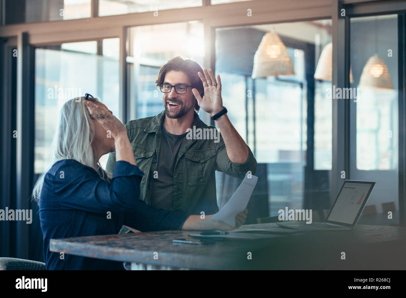 Zwei Geschäftskollegen geben einander hohe fünf und lächeln. Das Geschäftsteam freut sich über den Erfolg. Stockfoto