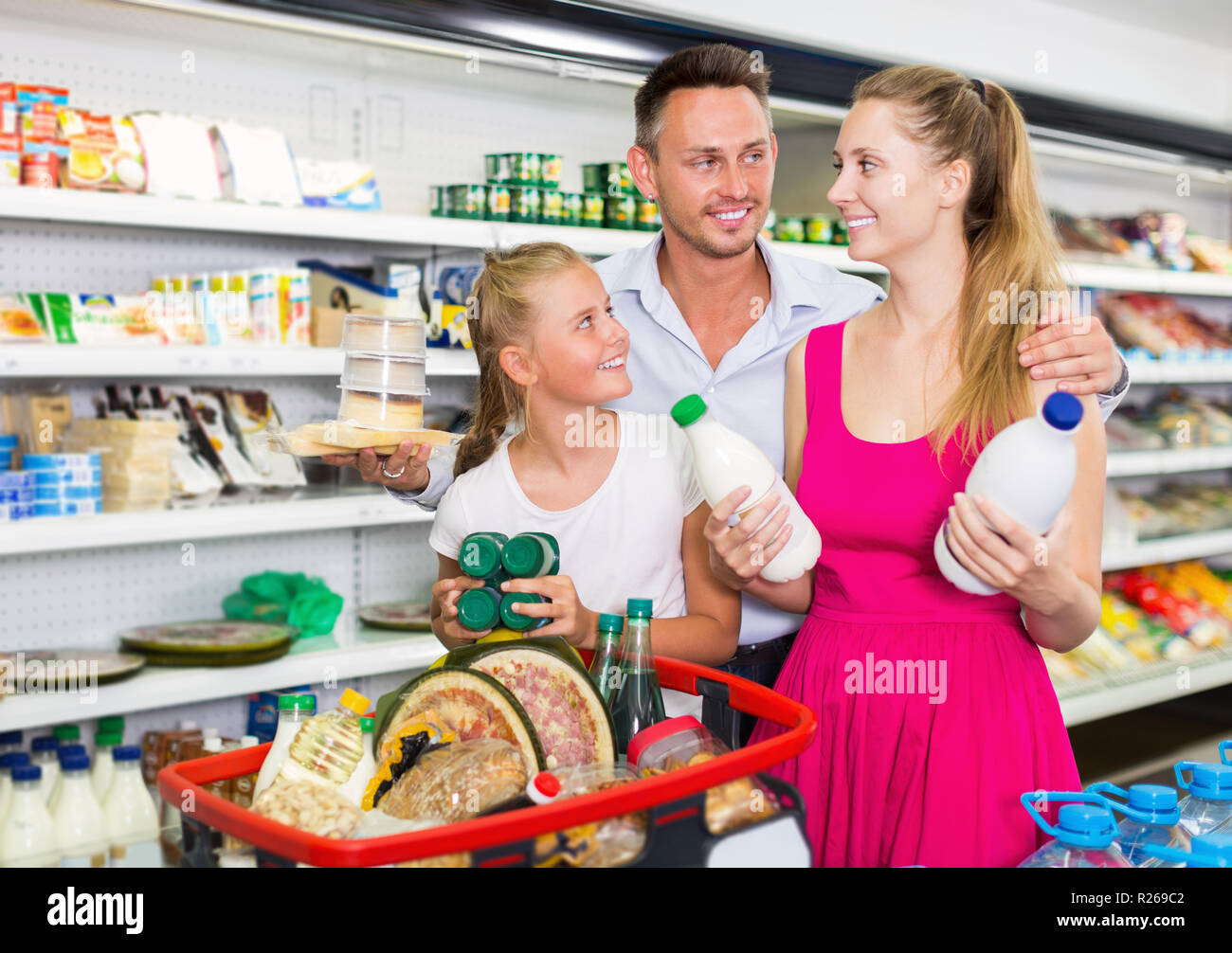 Positive junge Familie mit Kind Auswahl Milch und andere Produkte im Lebensmittel Shop Stockfoto