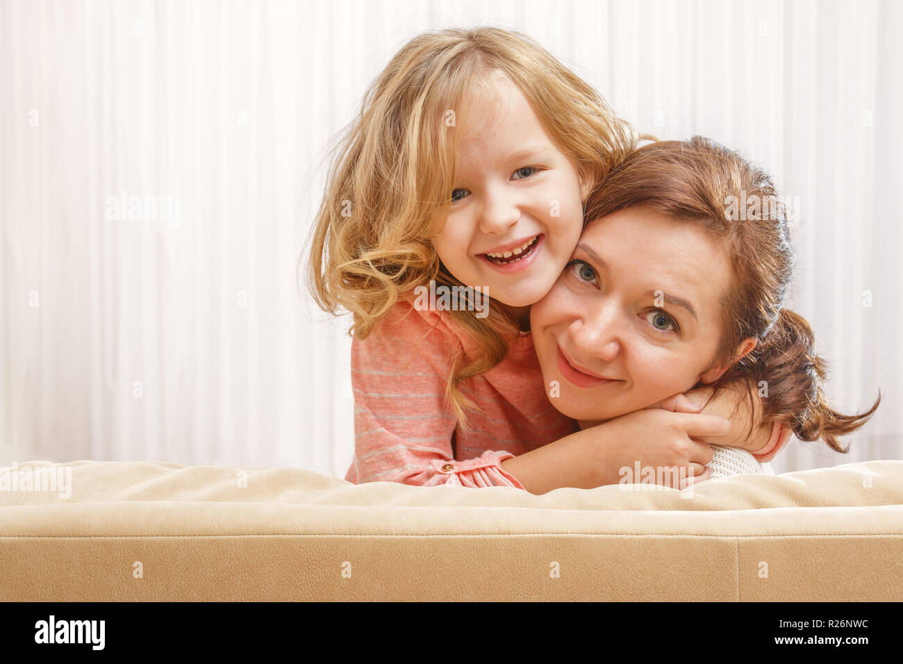 Glückliche Familie, Mutter und Tochter Vorschule Mädchen sitzen auf der Couch, umarmen und lächelnd Stockfoto