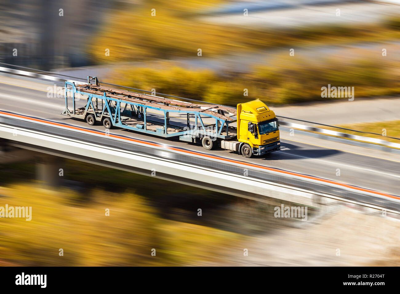 Gelbe Auto transporter schnell bewegte, an der Brücke im Herbst Stockfoto