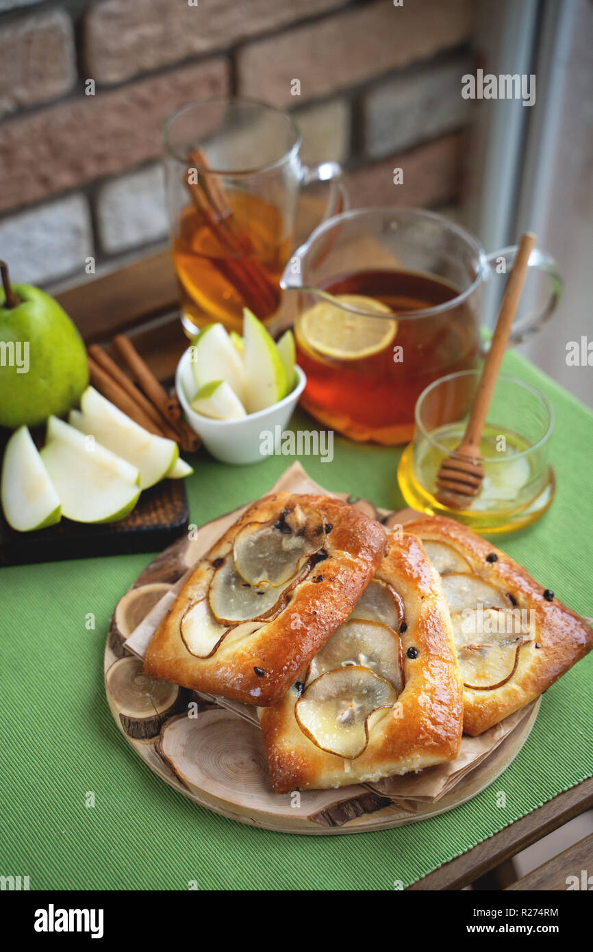 Französische brioche Brötchen mit Birne, Honig und Tee auf hölzernen Tisch Stockfoto