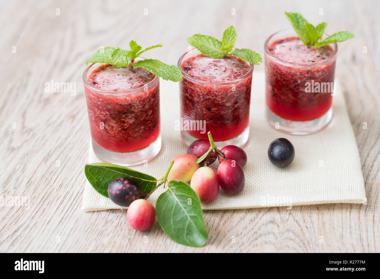 Frische organische Carissa carandas Saft auf Holzuntergrund mit frischen Früchten Stockfoto