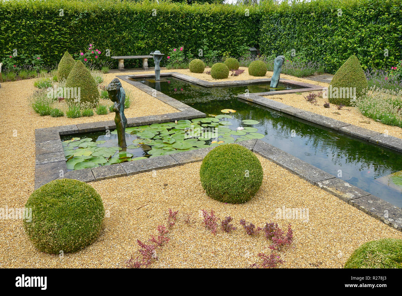 Wasserspiel IN EINEM LAND HAUS GARTEN. AUGUST 2018. OAKHAM, Rutland, England. Eine decortive formale Wassergarten mit Formschnitten und Statuen Stockfoto