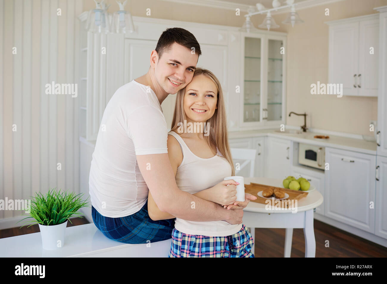 Junges Paar am Morgen in der Küche umfassen. Stockfoto