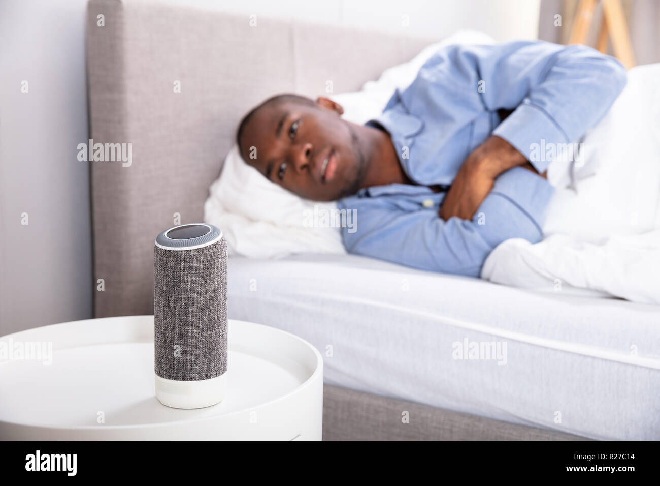 Afrikanischer Mann liegend auf Bett Musik auf kabellose Lautsprecher Stockfoto