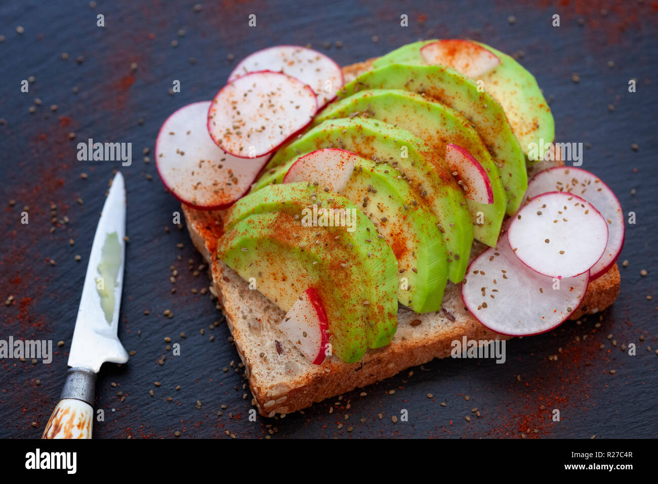 Avocado Toast. Toast Brot mit in Scheiben geschnittenen Avocado, rote Rübe, Sellerie Samen, Paprika. Close Up. Stockfoto