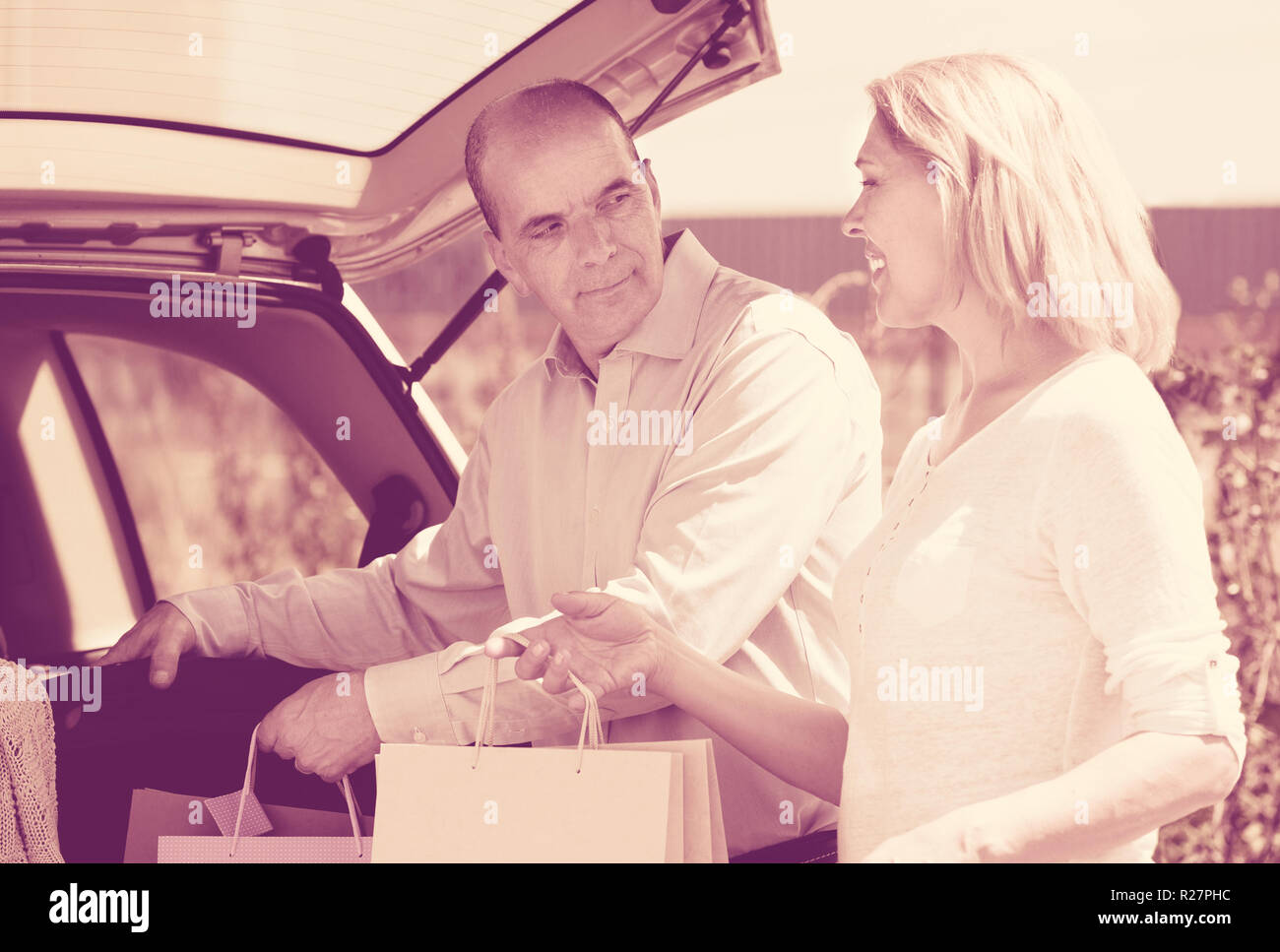 Glücklich reifer Mann und Frau in der Nähe von den Kofferraum des Autos mit Einkaufstüten in Händen Stockfoto