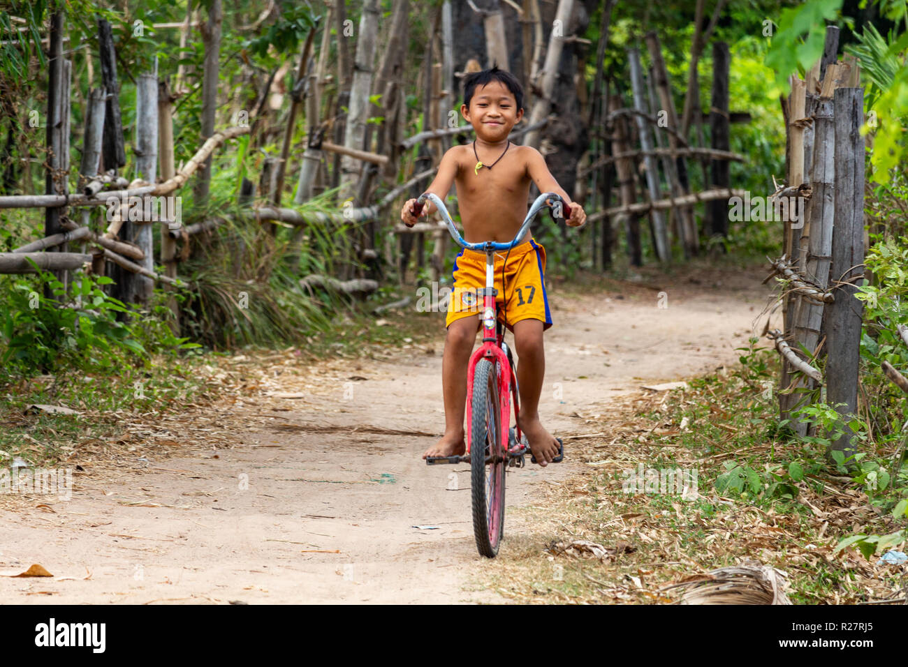 Don Det, Laos - 24. April 2018: Stolz kind Radfahren durch grüne im Südlichen Laos umgeben Stockfoto