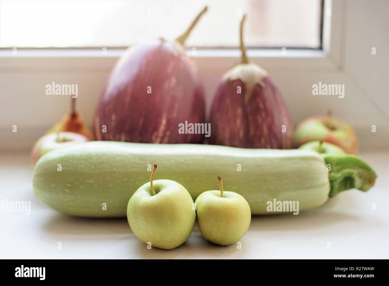 Ganze reife Squash, Äpfel, Auberginen liegen auf der Fensterbank. Stockfoto