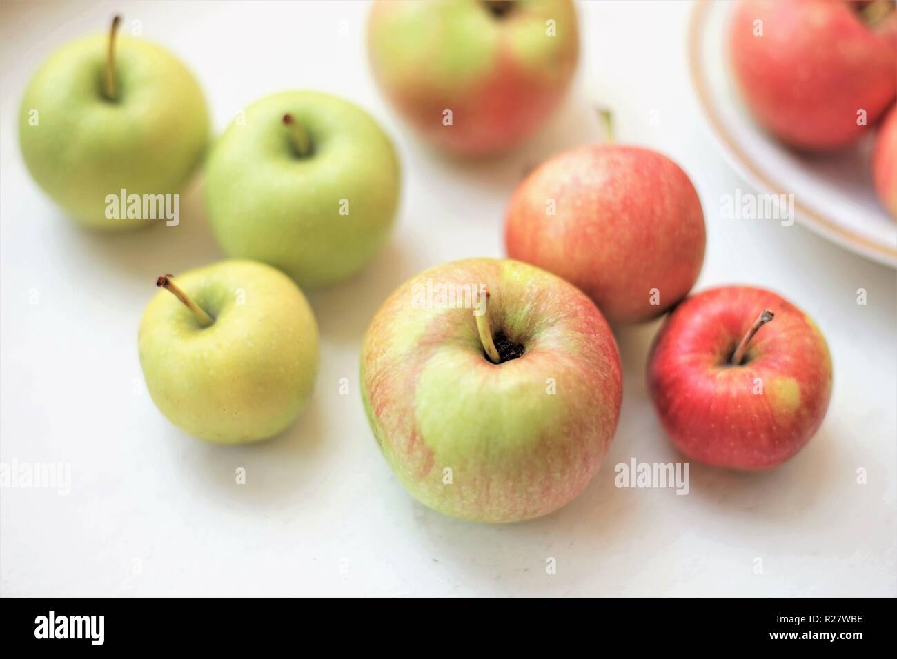 Mehrere ganze Äpfel auf einem weißen Tisch Stockfoto