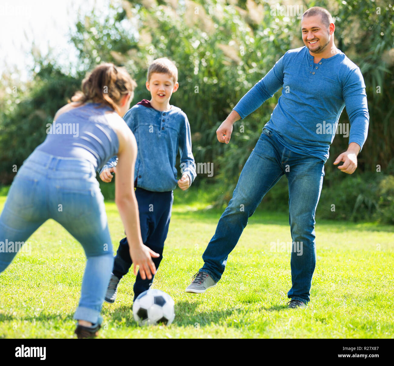 Portrait von aktiven positiven Familie Fußball spielen mit Sohn im Freien Stockfoto