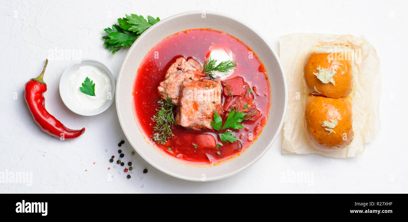 Borscht, rote Suppe aus roten Rüben und Gemüse mit Rippchen und saurer Sahne serviert mit Knoblauch Brötchen, traditionelle Gericht der ukrainischen, Russischen und P Stockfoto