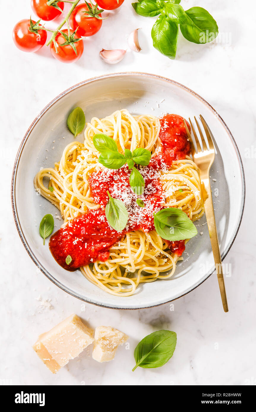 Pasta Spaghetti mit Tomatensoße und Käse Parmesan auf Platte auf dem marmortisch Hintergrund serviert. Nahaufnahme mit kopieren. Stockfoto