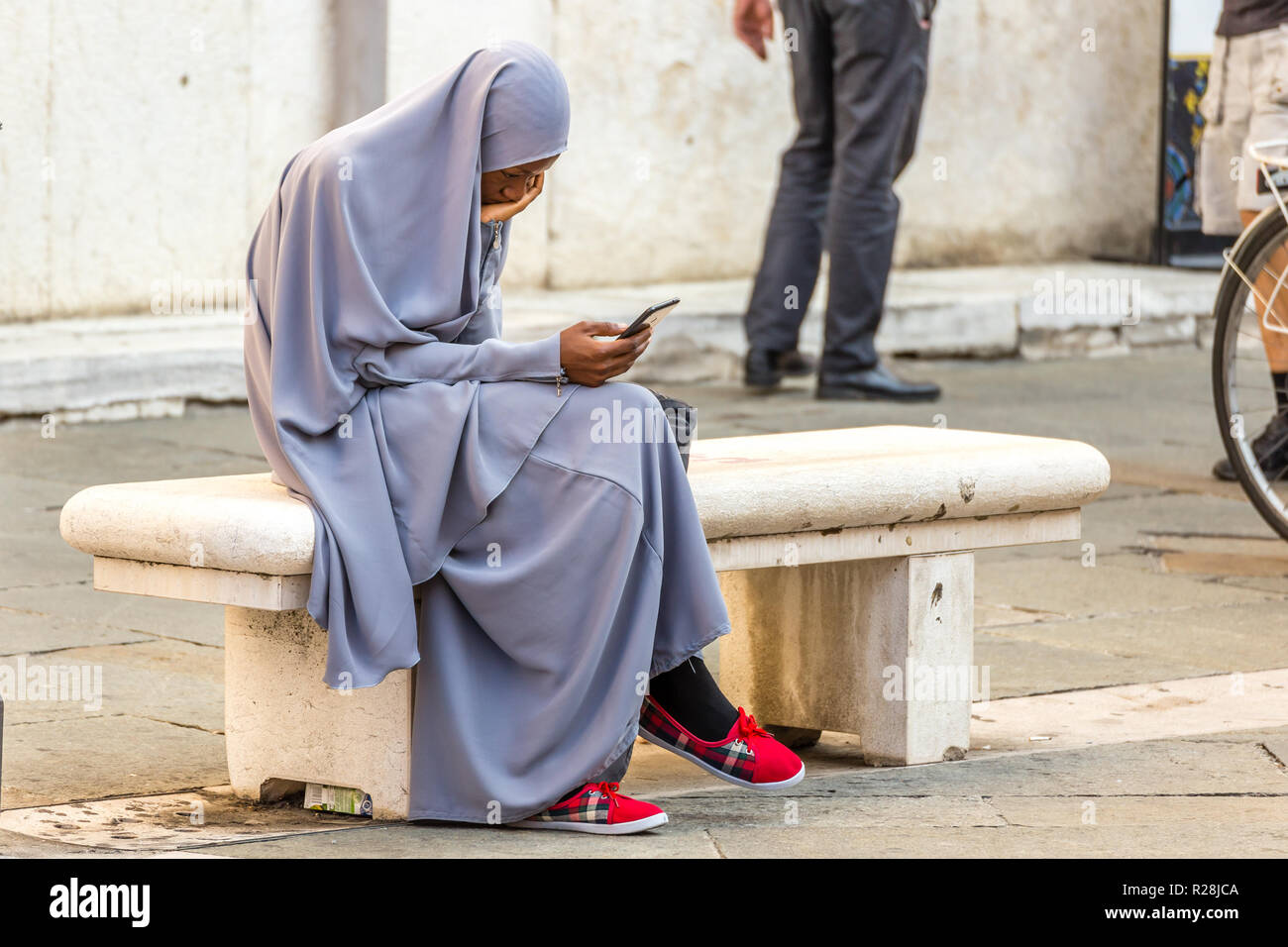 RAVENNA, Italien - 12 SEPTEMBER 2018: Mädchen mit abaya Kleid und mit smart phone auf der Piazza del Popolo, dem wichtigsten Platz des historischen Zentrums Stockfoto