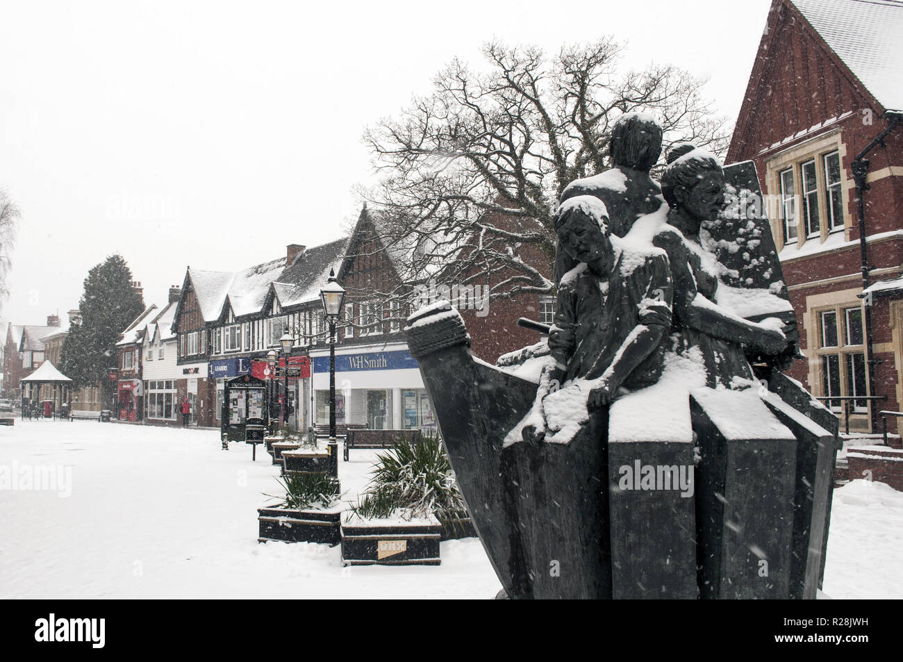 Ein Blick auf den Victoria Square Schnee in Droitwich bedeckt mit Geschäften und das Salz Bergleute Skulptur. Das Tier des Ostens Sturm. Stockfoto