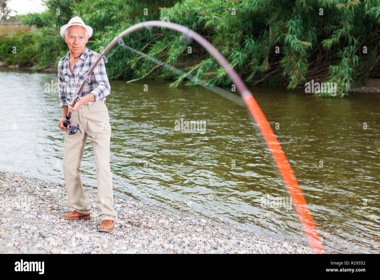 Reifen Fischer stehen auf Riverside und gehend, zu fangen Fische ziehen Stockfoto