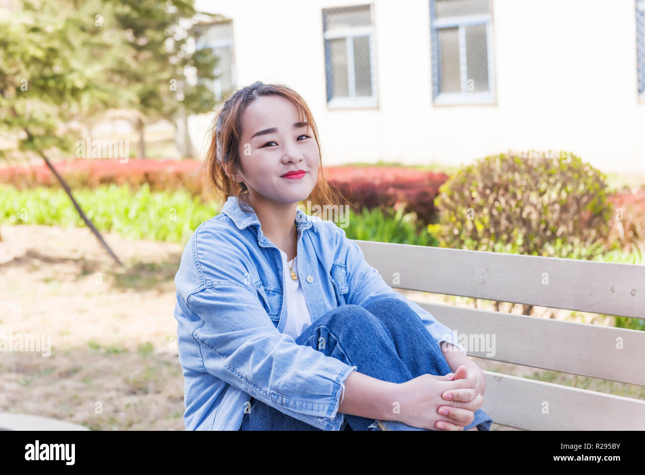 Junge Frau sitzt auf der Bank an der Universität Stockfoto