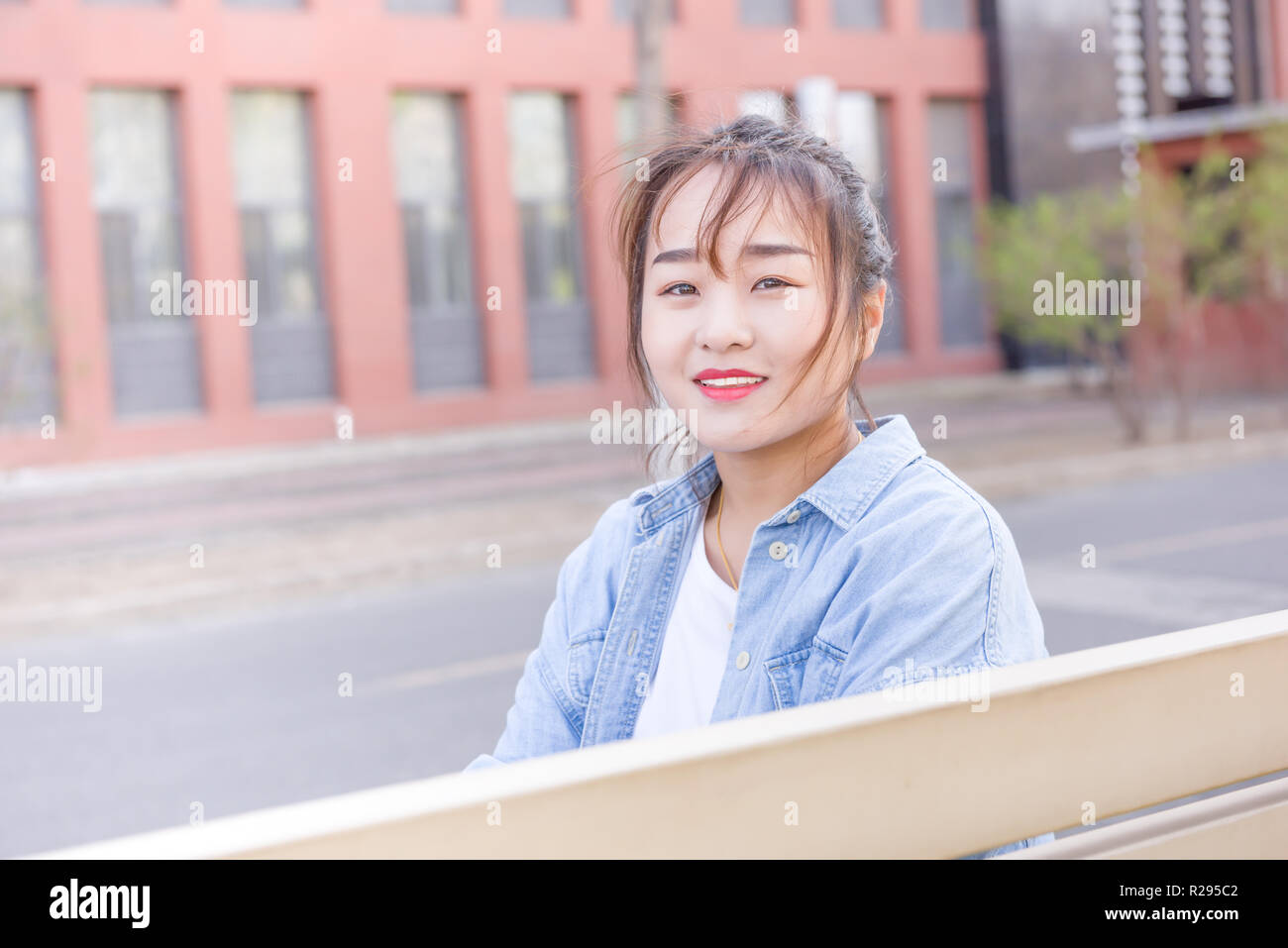 Junge Frau sitzt auf der Bank an der Universität Stockfoto