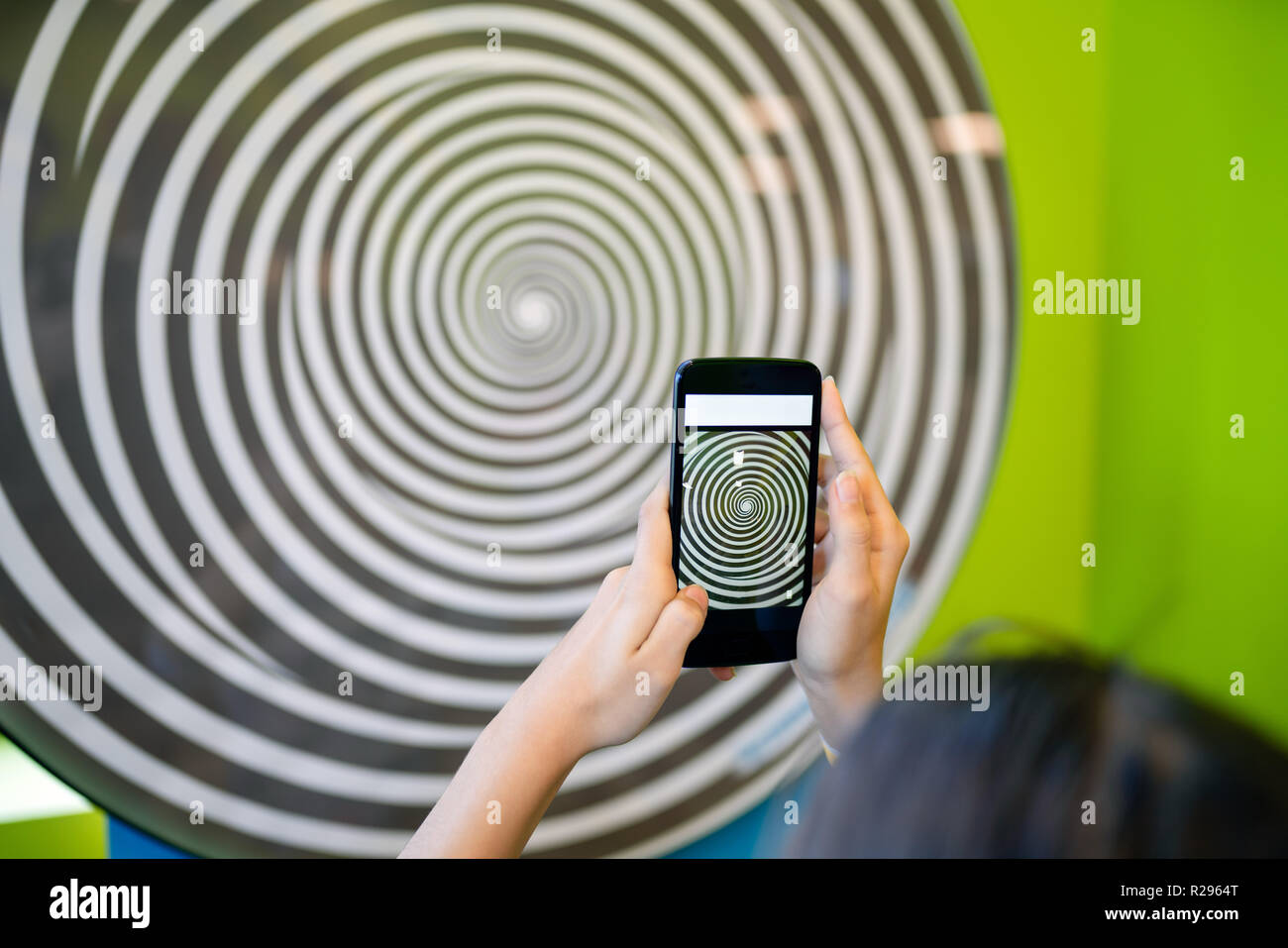 Junges Mädchen mit einem Smartphone, das hypnotisierende drehenden Spirale. Stockfoto
