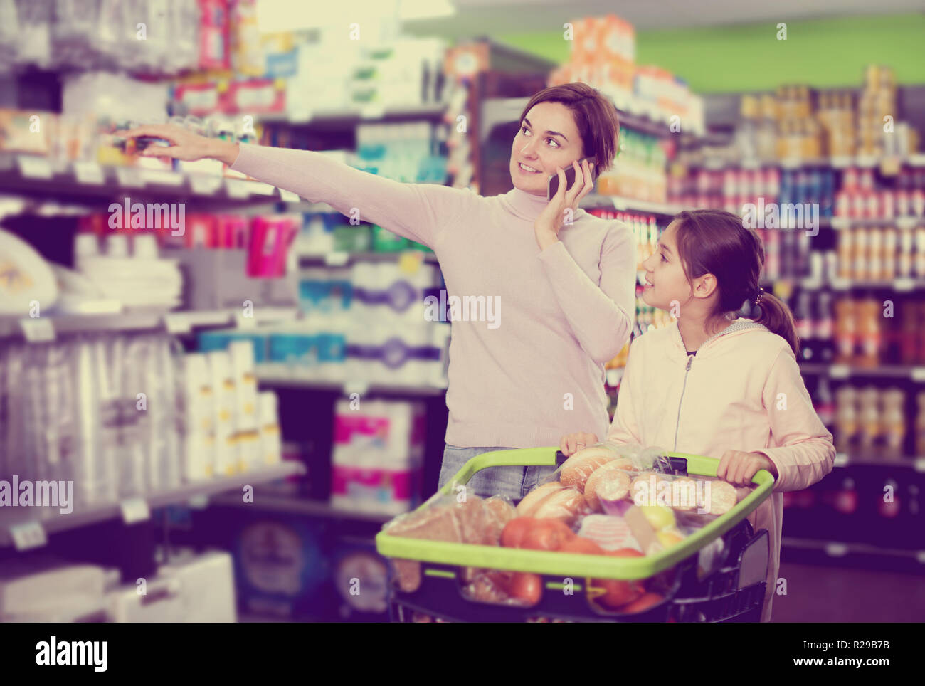 Glückliche junge Frau Kunde mit Mädchen telefonieren über das Einkaufen im Supermarkt zu konsultieren Stockfoto