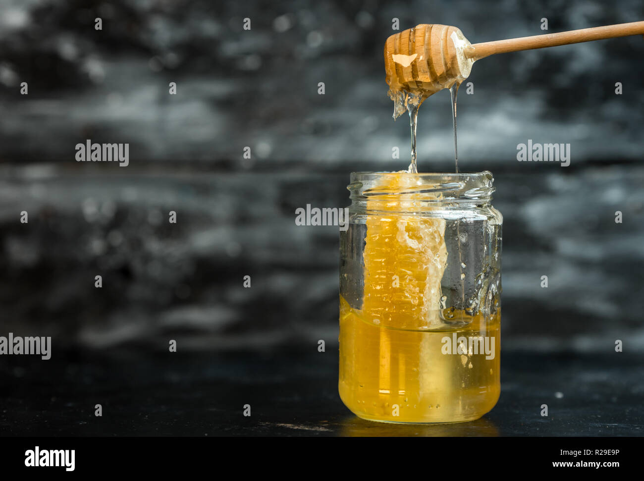 Natürliche, gesunde Zutat - ein Glas mit goldenen Honig auf einem dunklen Hintergrund Stockfoto