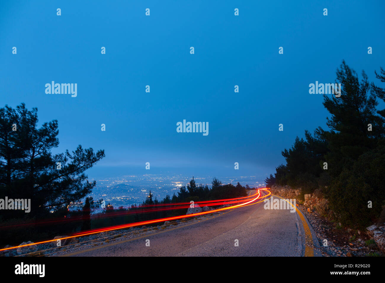 Auto Lampen auf dem Berg während der Blauen Stunde, an einem kalten Wintertag, in Berg Hymettus, in Athen, Griechenland. Stockfoto